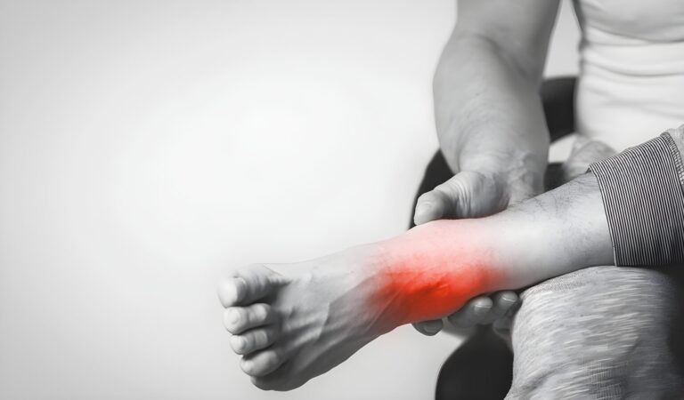 Hands examining a foot with the ankle highlighted in red