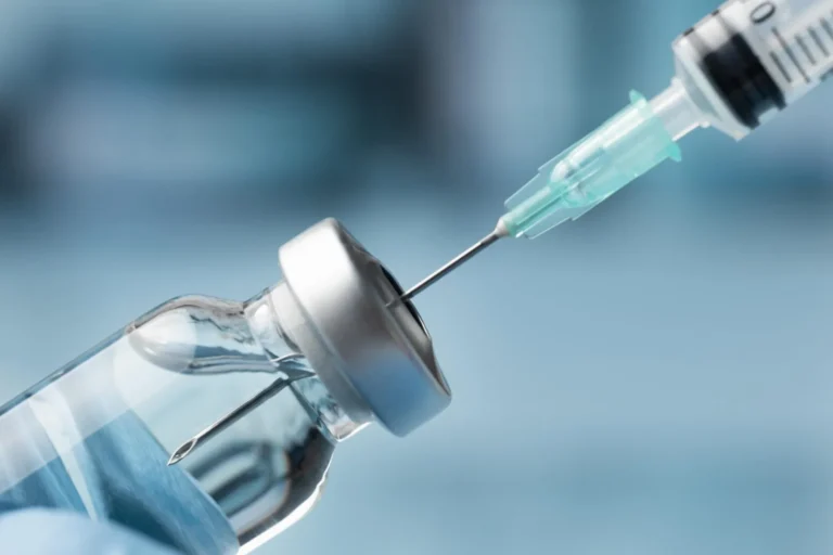 Syringe drawing liquid from a glass medication vial