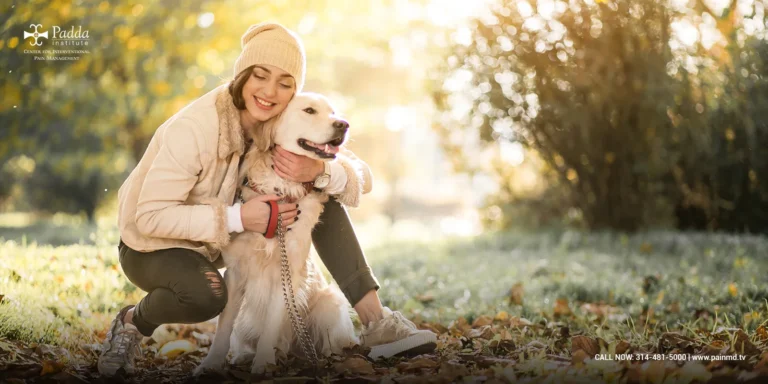 Woman crouching outdoors embracing a dog in autumn sunlight