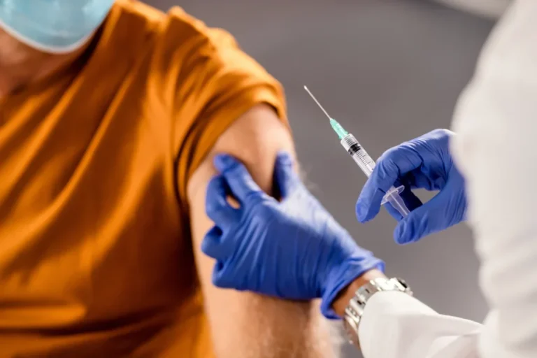 Gloved clinician administering an injection into a patient upper arm