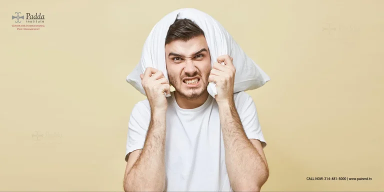 Man with a pillow over his head pressing his fingers into his ears