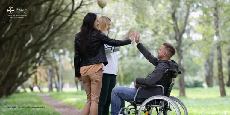 People greeting a man in a wheelchair on a tree-lined path