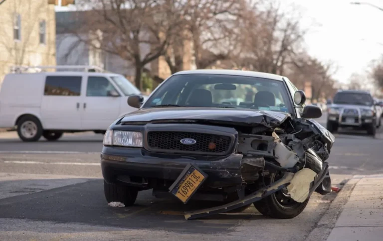 Car with severe front-end collision damage at a roadside