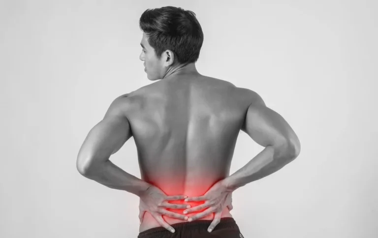 Bare back of a man with the lumbar spine highlighted in red to indicate low back pain