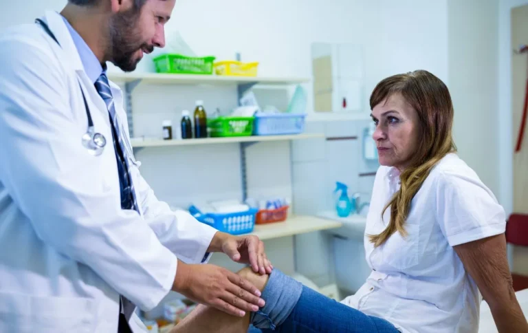 Physician examining an older woman's knee during a clinic visit