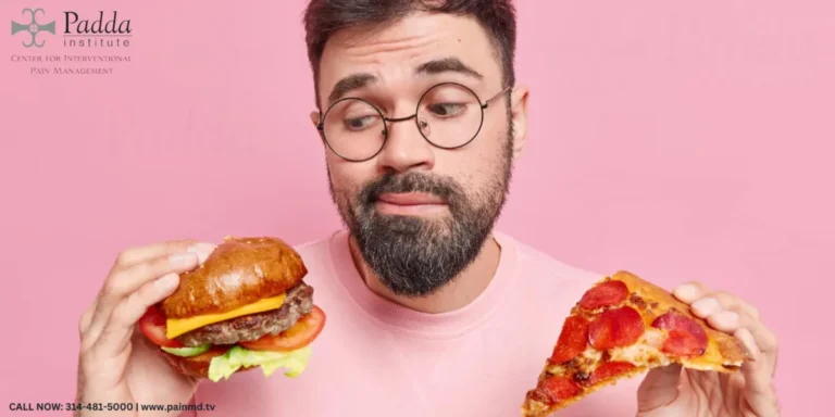 Man holding a burger and a slice of pizza against a pink background