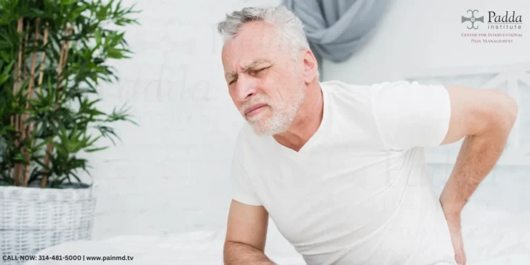 Older man in a white shirt holding his lower back