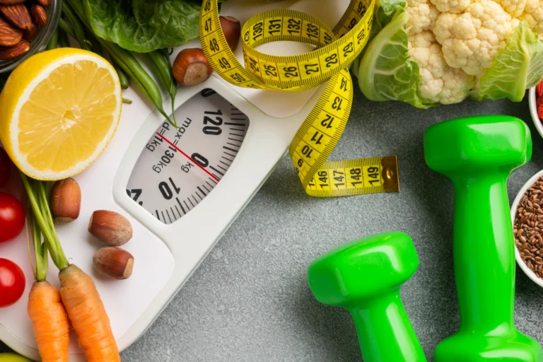 Bathroom scale surrounded by fresh vegetables, a tape measure and dumbbells