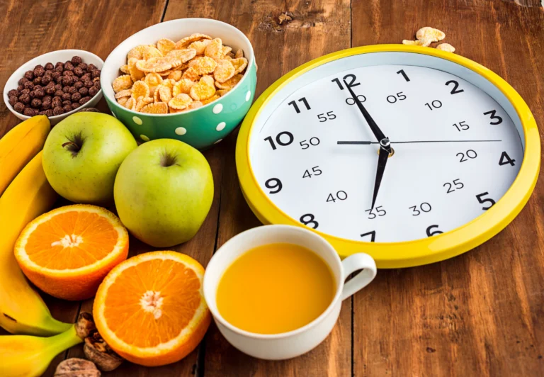 Breakfast cereal, fresh fruit and orange juice arranged around a large clock face, illustrating meal timing