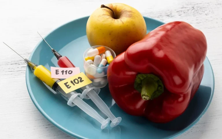 Apple and red pepper on a plate with syringes labelled with food additive codes