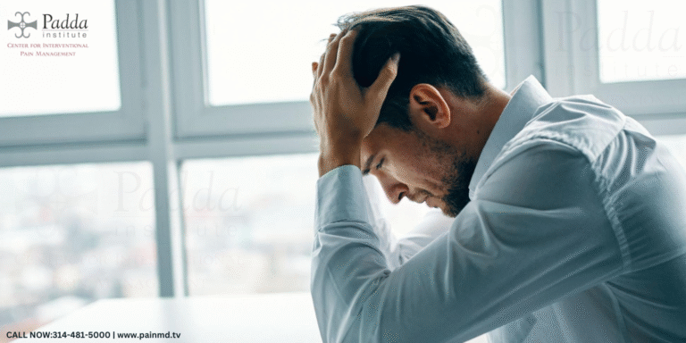 Man seated by a window holding his head in distress