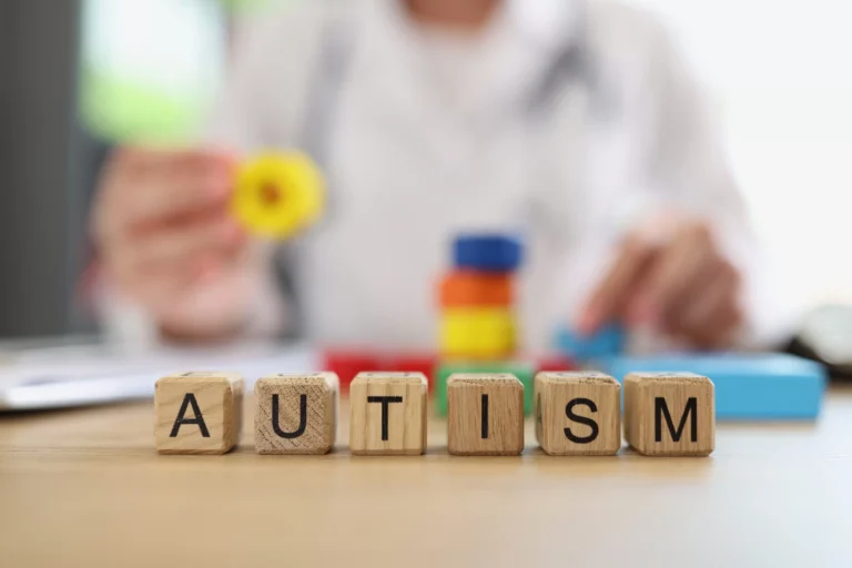 Wooden letter blocks spelling AUTISM on a clinician desk