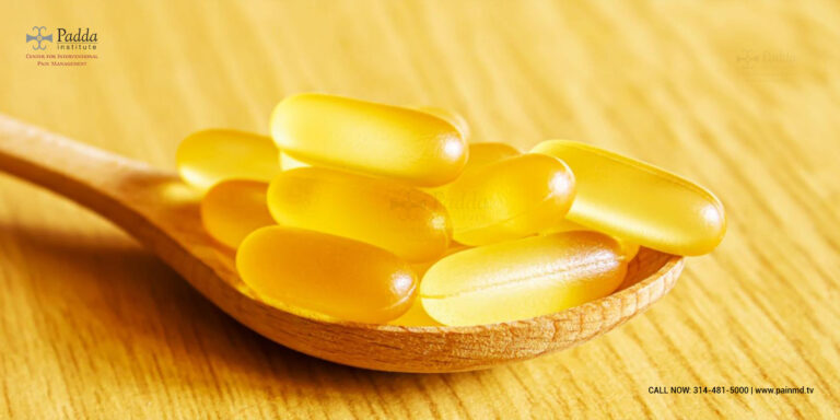 Yellow softgel capsules on a wooden spoon