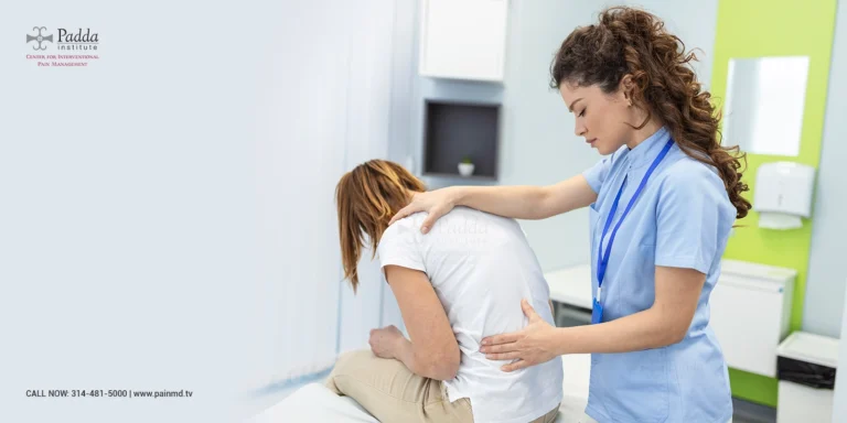 Nurse supporting a woman who is bending forward holding her lower back