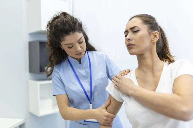 Nurse supporting a woman holding her arm in pain