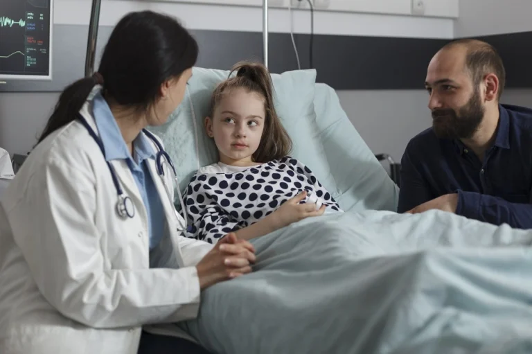 Doctor examining a child in a hospital bed with a parent beside them