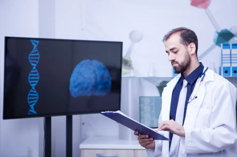 Clinician reviewing a brain scan and DNA graphic on a screen