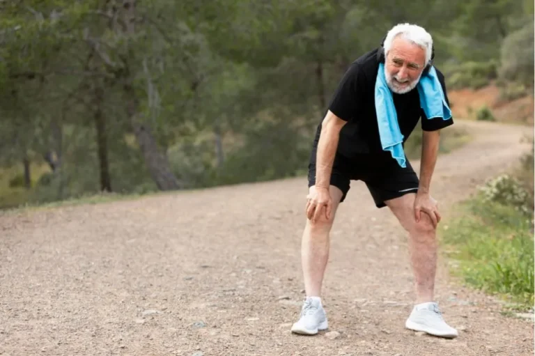Older man pausing to catch his breath during a run on a trail