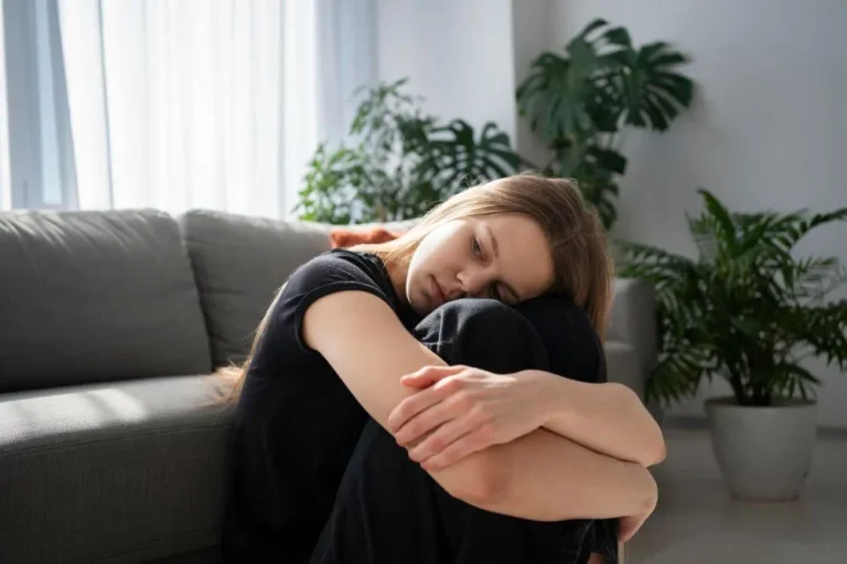 Woman curled up on a sofa with her head resting on her knees