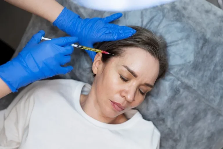 Gloved clinician injecting near the temple of a woman lying down