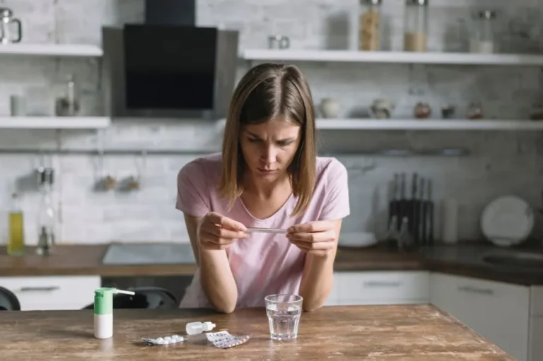 Woman at a kitchen table holding a tablet and a glass of water