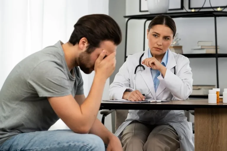 Man sitting with his head lowered while a doctor takes notes