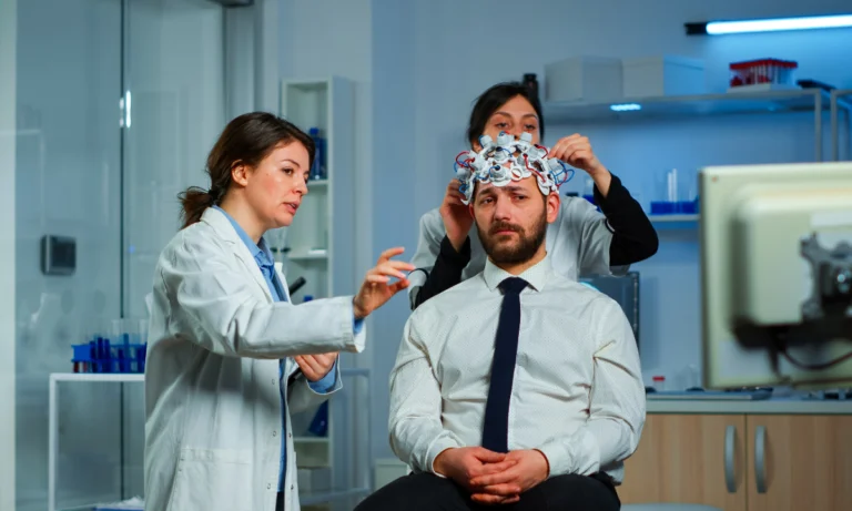 Laboratory staff fitting a cap of electrodes to a seated man