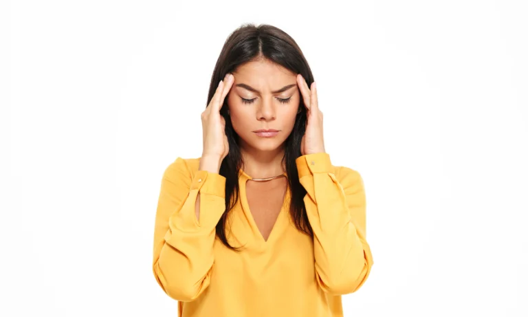 Woman in a yellow top pressing her fingers to her temples