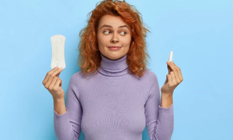 Woman holding a sanitary pad and a tampon against a blue background