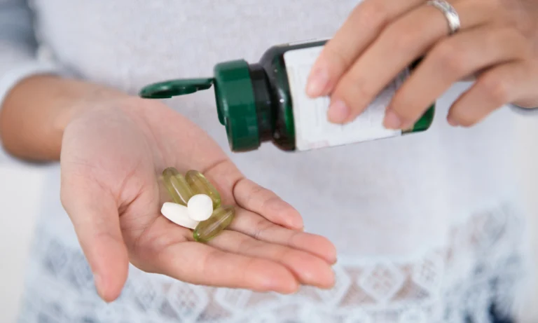 Hand tipping capsules from a supplement bottle into an open palm