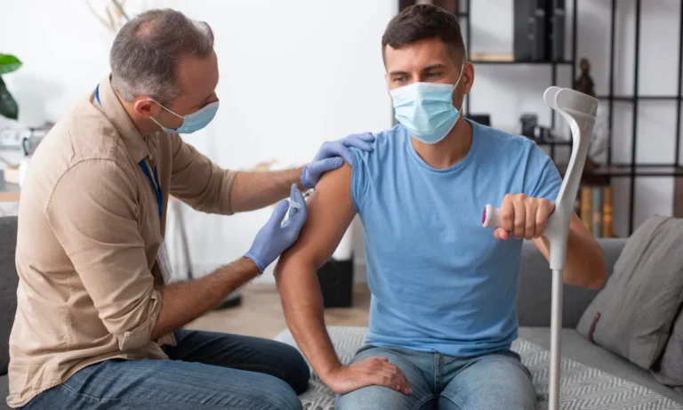 Clinician giving an injection to a seated man holding a walking stick