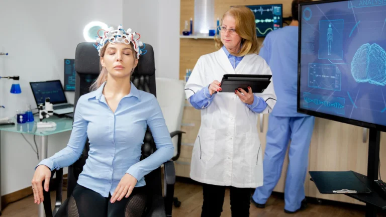 Woman wearing an EEG cap while clinicians monitor brain activity