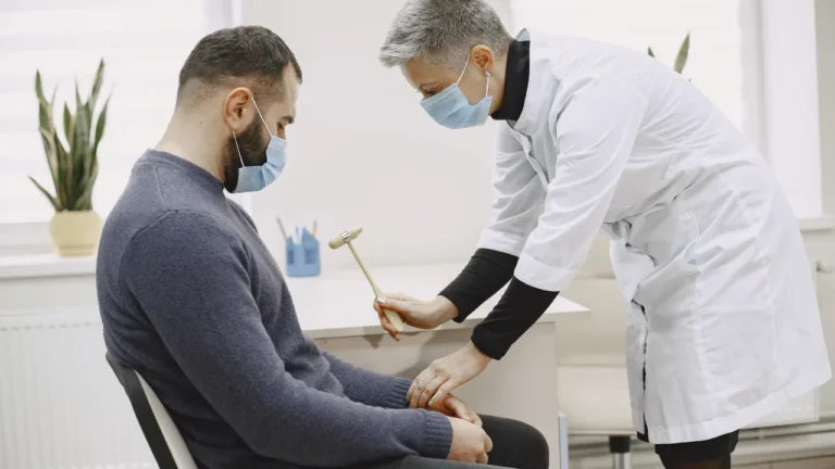 Clinician treating a seated man leg in a consulting room