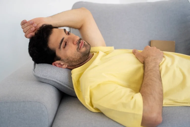Man lying on a sofa with one arm across his forehead