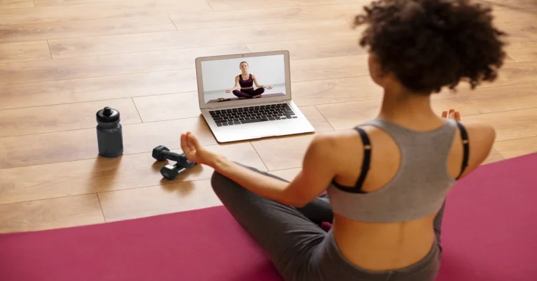 Woman practising yoga at home in front of a laptop