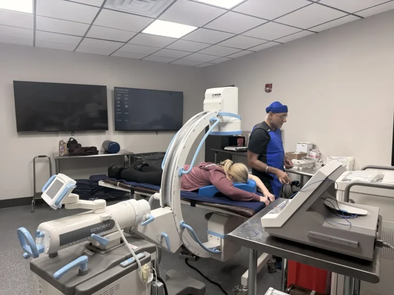 Wide view of the interventional procedure suite with C-arm fluoroscopy during a procedure at Padda Institute, St. Louis