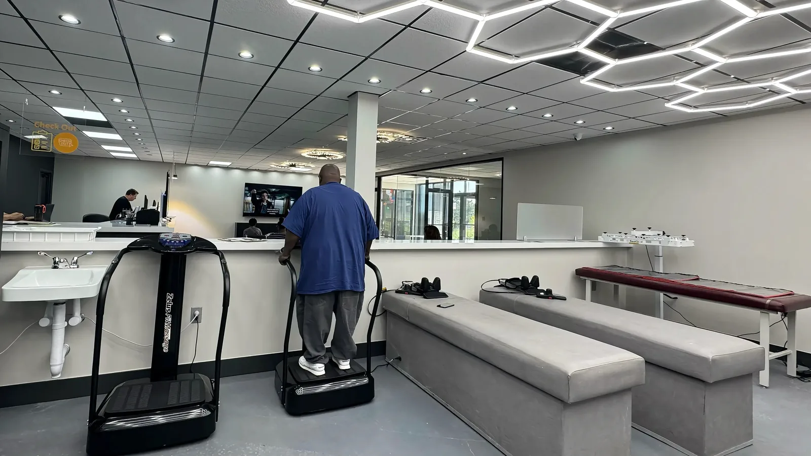 Patient standing on a whole body vibration platform in the therapy area at Padda Institute, St. Louis