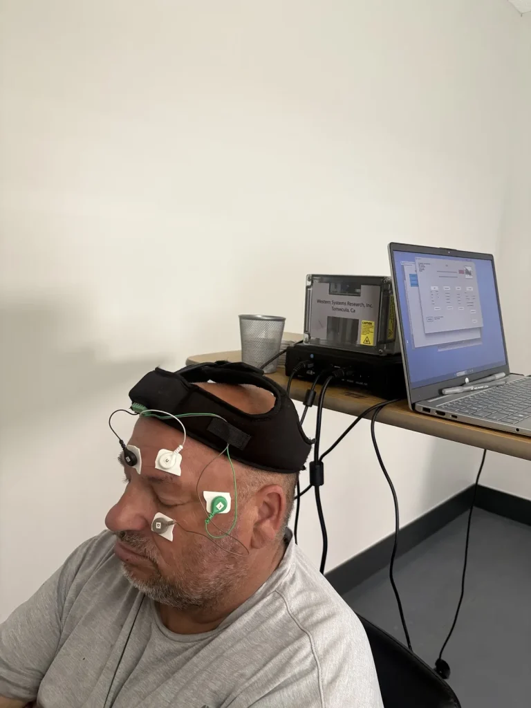 Patient wearing videonystagmography headgear with electrodes placed around the eyes while the recording unit and laptop capture eye movement during balance testing at Padda Institute, St. Louis