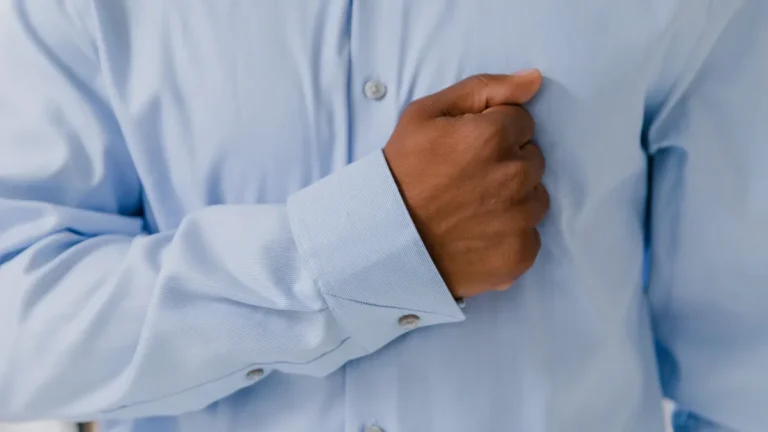 A man presses his hand against the front of his chest where costochondritis pain is felt