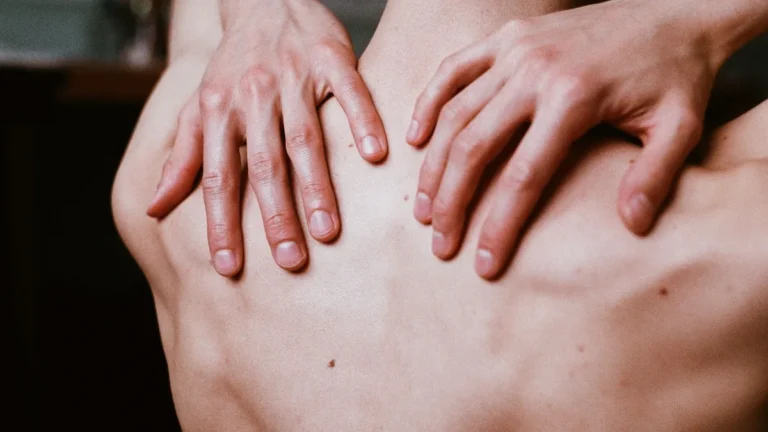 Hands pressed against the upper and middle back, where thoracic nerve pain starts