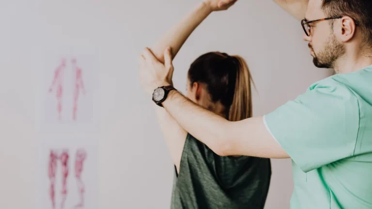 Clinician examining a patient's shoulder movement to assess the type of pain.